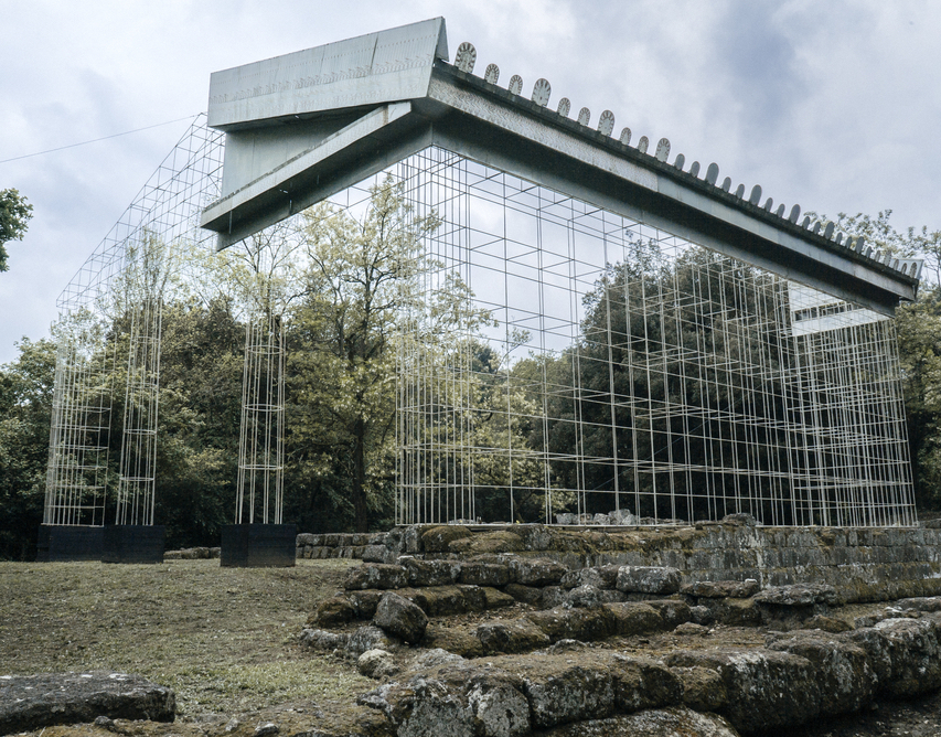 Stone ruins of an ancient temple, with modern frames and a partial roof showing what the temple looked like before it fell into disrepair